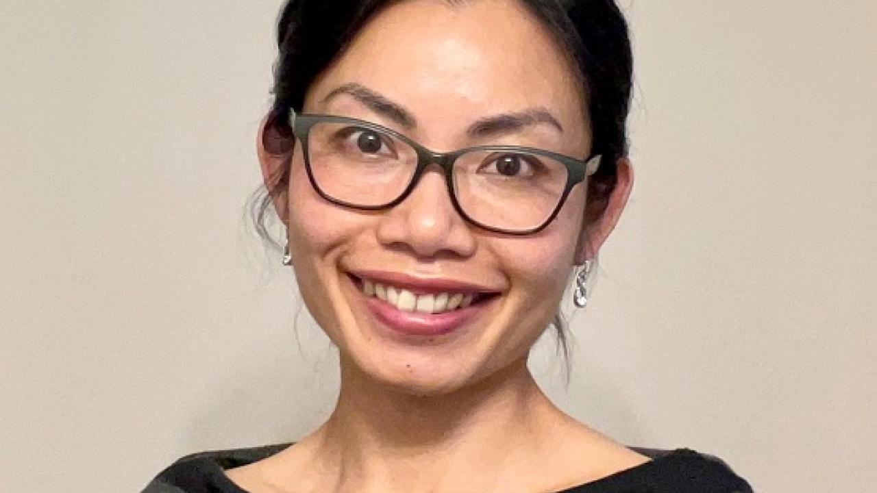 Amy Chen headshot pictured wearing a grey and black striped sweater. 